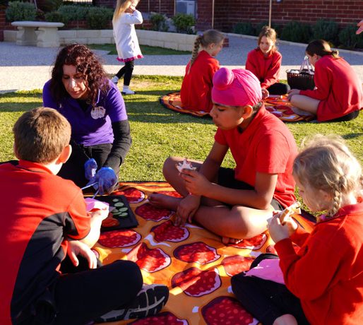 Educator and school-age children sharing a picnic on the lawn