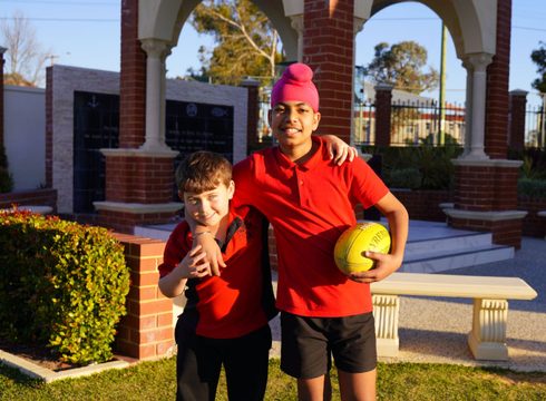 Two boys with a football outside