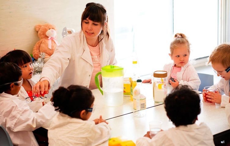 Kindy children in lab coats doing a science activity