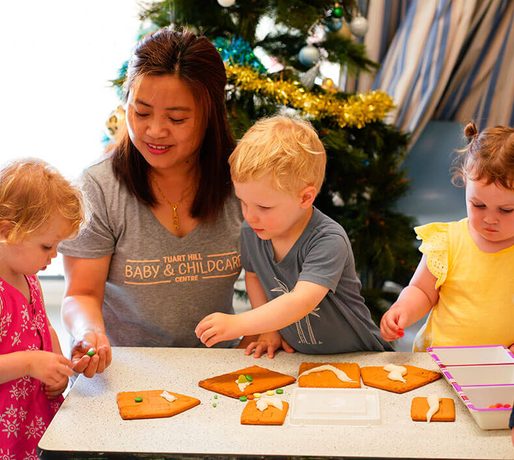 Educator and toddlers doing a craft activity at the table